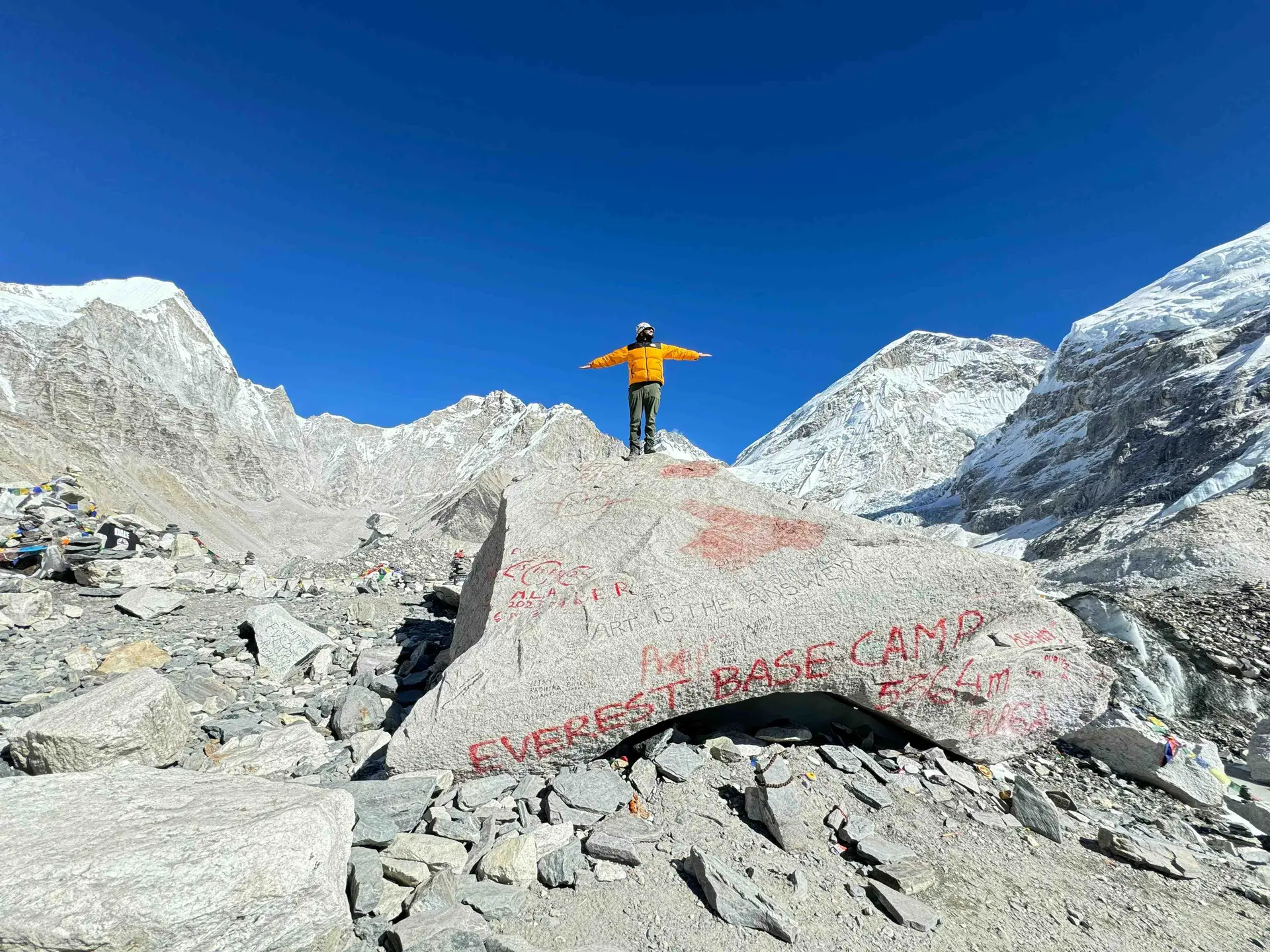 Trekker standing at Everest Base Camp celebrating success Himalayan expedition Nepal