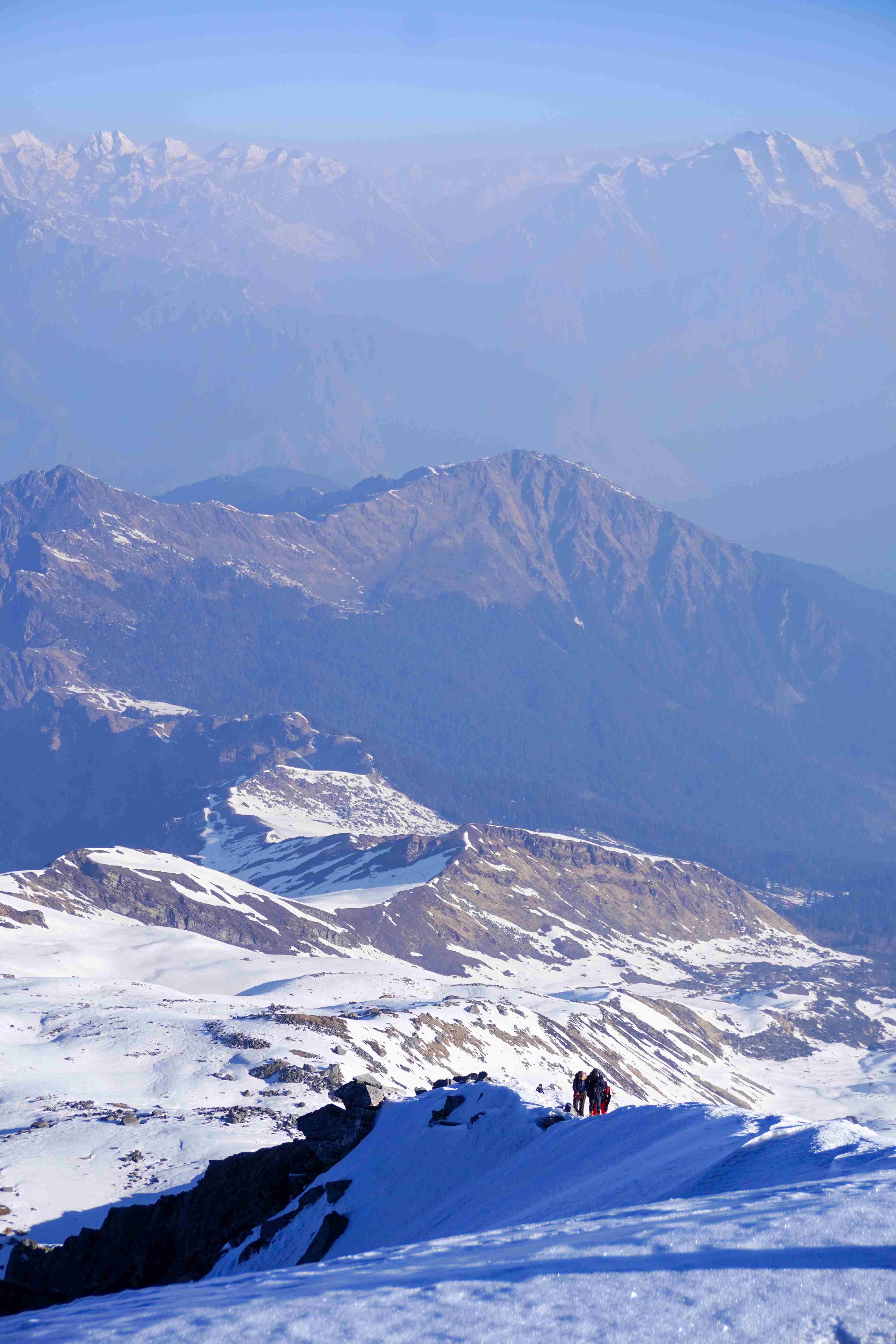 Trekkers ascending snowy slopes near Kedarkantha Summit during winter trek