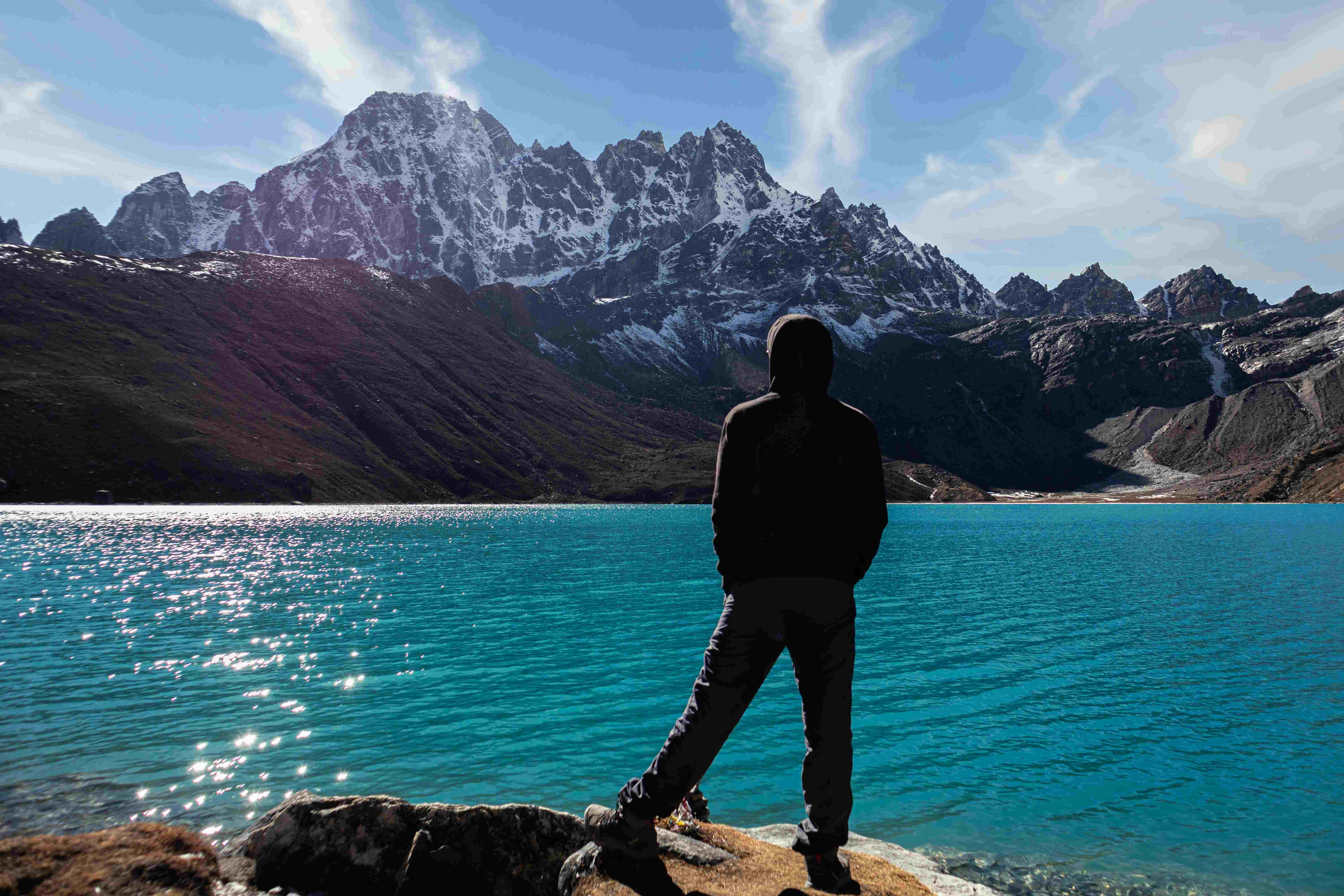 Solo trekker standing by the Gokyo Lakes enjoying mountain scenery.